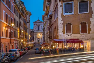 a city street at night with cars parked at Maison Medusa in Rome