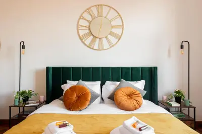 a bed with orange pillows and a clock on the wall at Piacentino Homes San Giovanni apartment in Rome