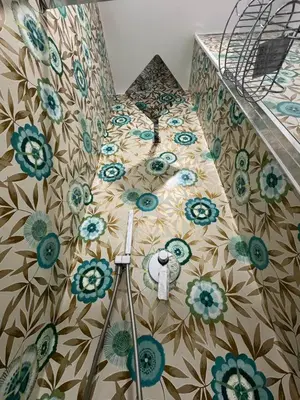 a bed with blue and green flowers on a wall at Fiorini - Rooms in Rome