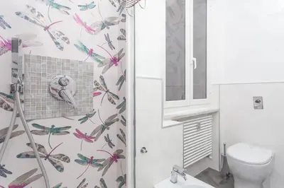 a bathroom with a toilet and butterflies wallpaper at Fiorini - Rooms in Rome