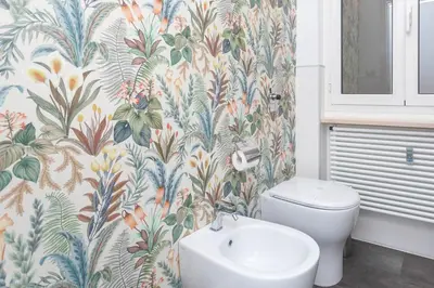a bathroom with a toilet and a flower wallpaper at Fiorini - Rooms in Rome