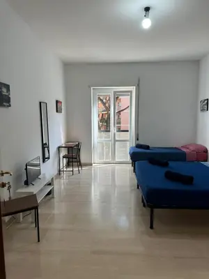a room with two beds and a table and a window at Palm Rooms in Rome