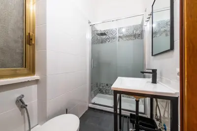 a white bathroom with a sink and a shower at Gianicolense Apartment in Rome