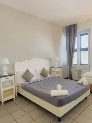 a bedroom with a bed and two tables and a window at Blancmaisonteveresuite in Rome