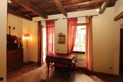 a room with red curtains and a table and a window at Bollo Studio in Rome