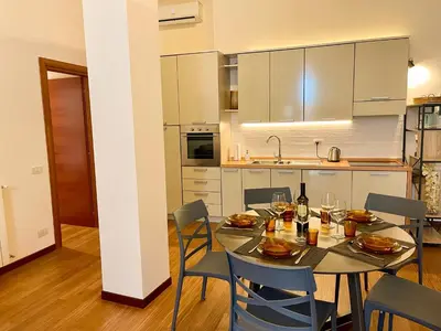 a kitchen with a table and chairs and a kitchen with white cabinets at Velabro Luxury Loft in Rome