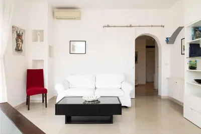 a white living room with a white couch and a red chair at Roma per te in Rome