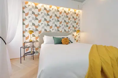 a bedroom with a white bed with a geometric headboard at YCH-Colorful and classy apartment near Fori Imperiali in Rome