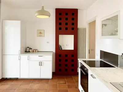 a kitchen with white cabinets and a red wall at DaliTourism - Vatican Apartment 77 in Rome