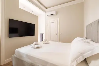 a white bedroom with a large bed with two towels at Vatican Clodio Suites in Rome