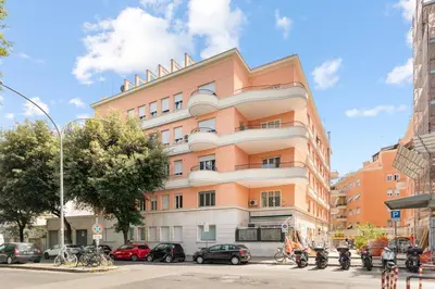 a pink building with cars parked in front of it at Vatican Clodio Suites in Rome