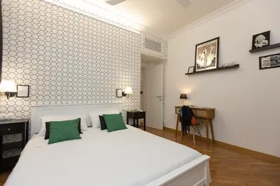 a bedroom with a white bed with two green pillows at Khris Home Apartments - Trastevere Parini in Rome