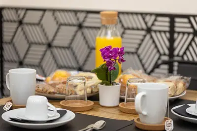 a table with plates and cups and a flower in a vase at Khris Home Apartments - Trastevere Parini in Rome