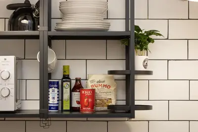 a shelf in a kitchen with dishes and wine bottles at Khris Home Apartments - Trastevere Parini in Rome