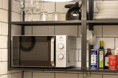 a microwave on a shelf in a kitchen at Khris Home Apartments - Trastevere Parini in Rome