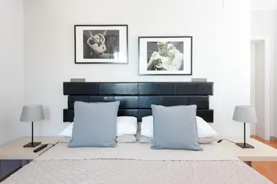 a bedroom with a black headboard and two pictures on the wall at La Lanterna Di San Pietro in Rome