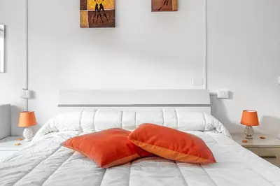 a white bed with two orange pillows on it at Dreamhome61 by Rentbeat in Rome