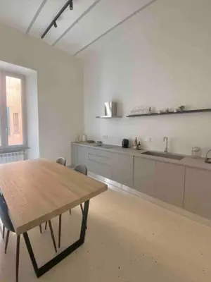 a large white kitchen with a wooden table in it at Boutique Via Veneto Apartment by SupaStays in Rome