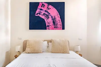 a bedroom with a bed with a pink painting on the wall at Boutique Via Veneto Apartment by SupaStays in Rome