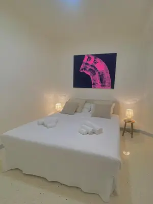 a white bed in a room with a painting on the wall at Boutique Via Veneto Apartment by SupaStays in Rome