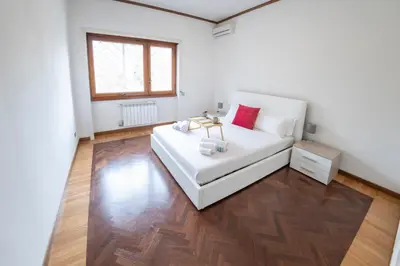 a bedroom with a white bed and a wooden floor at [10 min Vaticano] Big home Balduina con piscina in Rome
