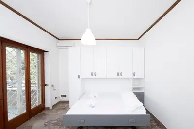 a white bedroom with a large bed and a door at [10 min Vaticano] Big home Balduina con piscina in Rome