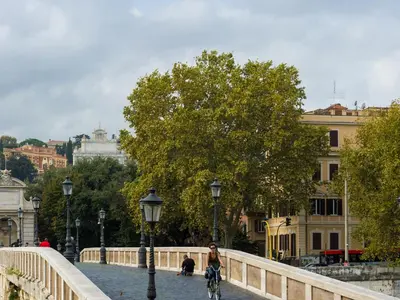 a woman riding a bike on a bridge at Tree Charme Trilussa in Rome