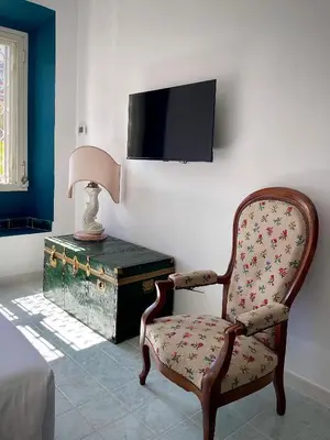 a bedroom with a chair and a table with a tv at Casetta Roma San Giovanni in Rome