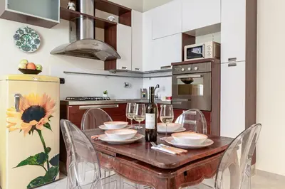 a kitchen with a wooden table with chairs and a refrigerator at Hostly-Volturno Suite Apartment-Center of Rome in Rome