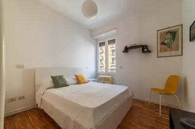 a white bedroom with a bed and a chair at GuestHost - Chic Stay at Magnagrecia Rome Apartment in Rome
