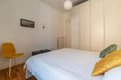 a bedroom with a white bed and a yellow chair at GuestHost - Chic Stay at Magnagrecia Rome Apartment in Rome