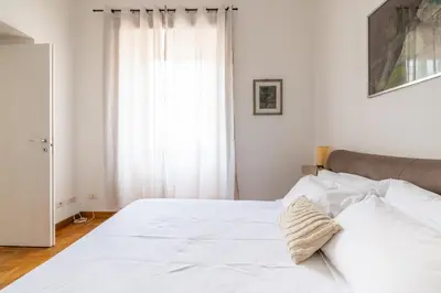 a white bed in a white bedroom with a window at DOMUS GIULIA in Rome