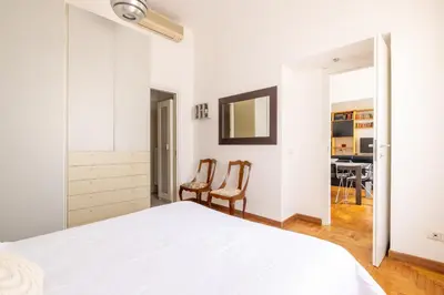 a white bedroom with a bed and two chairs at DOMUS GIULIA in Rome