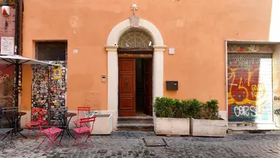 an orange building with red chairs and a wooden door at Sciampagne in Rome