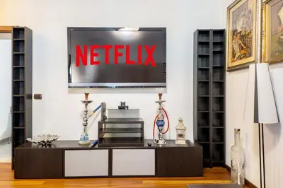 a living room with a netflix sign on the wall at HOME Suitte in San Giovanni near Basilica - Roma - in Rome