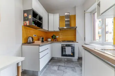 a kitchen with white cabinets and yellow tiles at Casilina Green House - Metro Malatesta & Wi-Fi in Rome