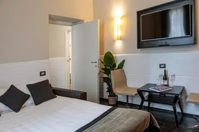 a hotel room with a bed and a desk and a tv at The Independent Suites in Rome