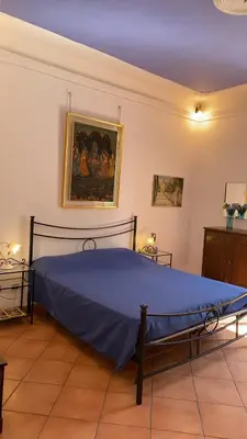 a bedroom with a blue bed with a painting on the wall at Colosseum home in Rome