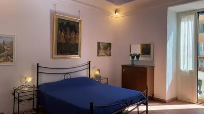 a bedroom with a blue bed and a painting on the wall at Colosseum home in Rome