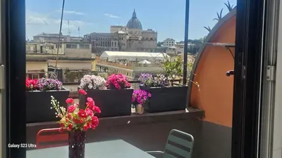 a table with flowers on a balcony with a view at Vatican Roma Caput Mundi in Rome