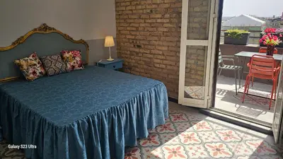 a bedroom with a bed and a balcony with a table at Vatican Roma Caput Mundi in Rome