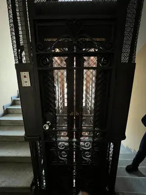 a black iron door with stairs in a building at S.Pietro Elvira's retro apartment in Rome