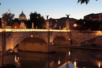 a bridge over a river in a city at night at Residenza San Martino in Rome