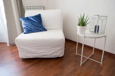 a white couch with a blue pillow next to a table at Domus Crescenzio - Guest House in Rome