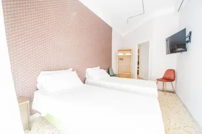 two beds in a white room with a tv at Trastevere Lovely 2 BR Apartment in Rome