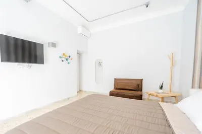 a white bedroom with a bed and a chair at Trastevere Lovely 2 BR Apartment in Rome