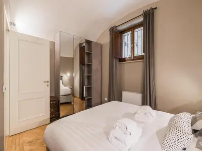 a bedroom with a white bed and a mirror at The Best Rent – Charming flat near Colosseo in Rome