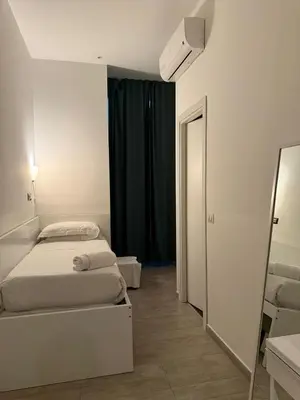 a small bedroom with a bed and a mirror at Relais Merulana Guest House in Rome