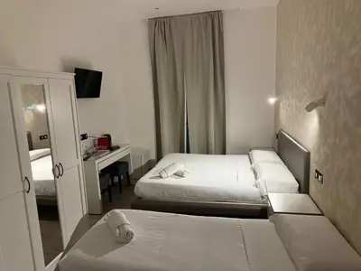 a hotel room with two beds and a desk at Relais Merulana Guest House in Rome
