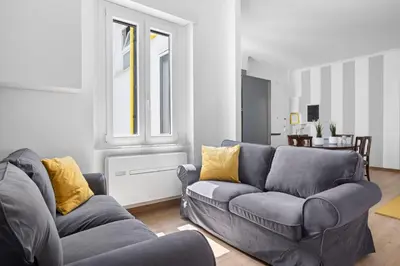a living room with a gray couch and yellow pillows at Sunny House Gianicolo in Rome